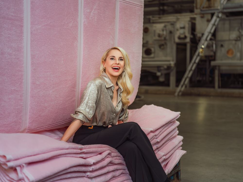 Silvia Schneider auf gestapelter rosa Frottierware in der Vossen Produktion